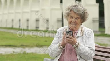 老年妇女在户外手持<strong>银色</strong>智能<strong>手机</strong>